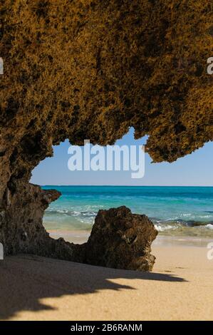 Vista attraverso una grotta di corallo su una spiaggia di sabbia sulla baia di Osprey nel Cape Range National Park nell'Australia Occidentale. Foto Stock