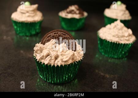 Cupcake Decorati verdi per compleanno o evento con pezzi di biscotto crumbles e glassa Foto Stock