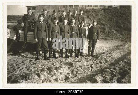 Groep Wehrmaktsoldaten un gruppo di membri della Wehrmacht che posano sulla spiaggia, una coppia seduta su una barca di legno. In totale 13 uomini. Produttore : fotografo: Anonymous place manufacturing: Netherlands Data: Giu 1940 - 1941 caratteristiche Fisiche: Gelatina argento materiale di stampa: Carta Tecnica: Gelatina argento stampa dimensioni: H 6 cm. B × 9 cm. Oggetto: Occupazione  oorlogla società, l'unità, la troop  servizio militare seconda guerra occupazione dei Paesi Bassi Quando: 1940 - 1941 Foto Stock
