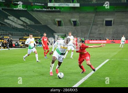 Monchengladbach, Germania. 11th Mar, 2020. Breel Embolo (fronte, L) di Monchengladbach vies con Ellyes Skhiri di Colonia durante una partita tedesca della Bundesliga tra la Borussia Monchengladbach e il FC Colonia a Monchengladbach, Germania, 11 marzo 2020. A causa dello scoppio del COVID-19, la partita è stata tenuta a porte chiuse per la prima volta nella storia della Bundesliga, accordandosi ai media tedeschi. Credit: Ulrich Hufnagel/Xinhua/Alamy Live News Foto Stock