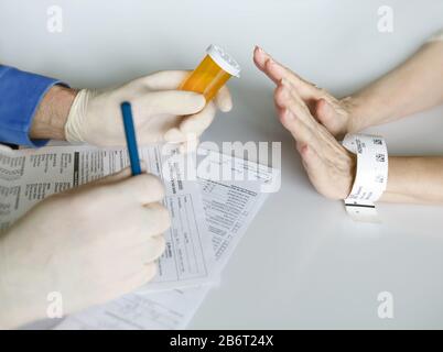 Le mani del medico davanti alle mani del paziente, mentre il paziente rifiuta i medicinali prescritti. Foto Stock