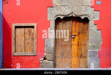 Vecchia casa, un muro rosso, una finestra a bordo e una porta chiusa in legno. Foto Stock