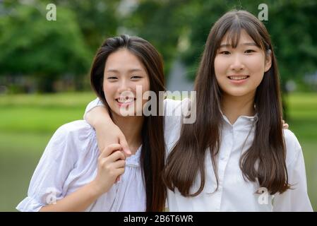 Due giovani felici belle ragazze asiatiche adolescenti che si uniscono al parco Foto Stock