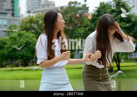 Due giovani felici belle ragazze asiatiche adolescenti che si divertono insieme al parco Foto Stock