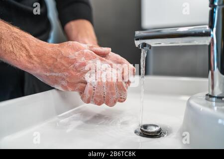 Corona virus Travel prevenzione uomo mostrando igiene delle mani lavando le mani con sapone in acqua calda per coronavirus germi diffusione protezione. Foto Stock