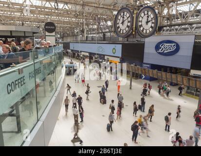 I clienti di una caffetteria della stazione ferroviaria di Waterloo si affacciano sui viaggiatori in treno mentre si muovono in una macchia da e per lungo l'atrio principale in un pranzo feriale. Foto Stock
