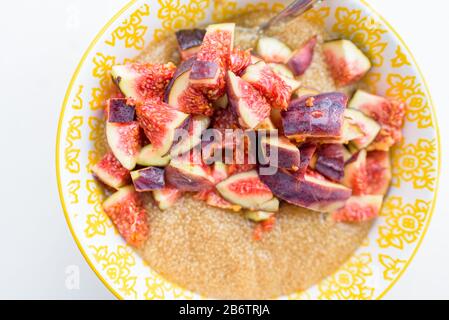 Porridge di amaranto per la prima colazione con i fichi in una ciotola gialla vista superiore Foto Stock