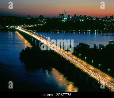 Ponte di Paton illuminato e monumento Motherland a Kiev. Foto Stock