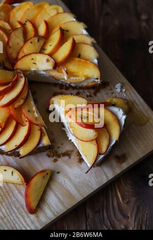 Cheesecake fatto in casa con pesche. Dessert di frutta salutare con formaggio spalmabile, nettarine, miele e timo su tavola di legno. Torta dietetica Foto Stock