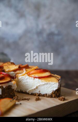 Cheesecake fatto in casa con pesche. Dessert di frutta salutare con formaggio spalmabile, nettarine, miele e timo su tavola di legno. Torta dietetica Foto Stock