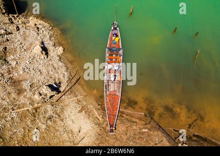 Vista aerea di una tradizionale barca a coda lunga in legno su un enorme lago circondato da scogliere calcaree (Khao Sok) Foto Stock