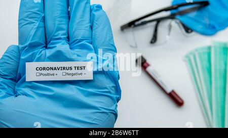 Scienziato con guanti blu contiene l'etichetta identificativa della provetta con campione di sangue infetto per COVID-19, nuovo coronavirus trovato a Wuhan, Cina. Foto Stock