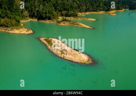 Vista di un drone su una piccola isola in un grande lago circondato da giungla tropicale (Cheow Lan Lake, Khao Sok) Foto Stock