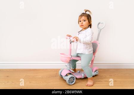 Bambino seduto su scooter a casa. Copia spazio Foto Stock