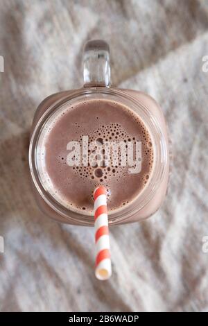 Milkshake di cioccolato fatto in casa nel New England in un Bicchiere di vetro Mug su panno, vista dall'alto. Vista dall'alto, dall'alto, disposizione piatta. Primo piano. Foto Stock