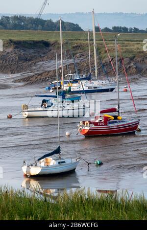 Gli yacht si aggirano alle ormeggi sul letto del fiume di marea, fiume Parrett, Burnham-on-Sea, Somerset, Inghilterra Foto Stock