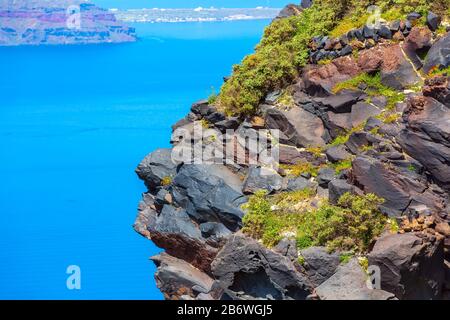 Santorini, Grecia grande roccia vulcanica pietra e caldera, mare, fiori e vulcano isola sfondo Foto Stock