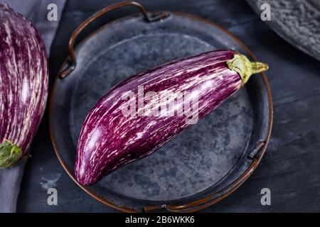 'Graffiti Eggplant', variante a forma di goccia con righe di viola con pelle bianca avorio su vassoio di ferro Foto Stock