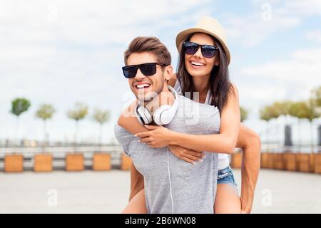 Uomo bello carring la sua ragazza sorridente sul retro. Foto Stock