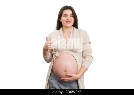 Madre positiva futura che fa i pollici-in su il gesto isolato su sfondo bianco come concetto sano di fertilità Foto Stock