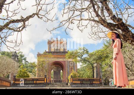 Vietnam, città storica di Hue. Una giovane donna vietnamita in un abito tradizionale Ao dai al Mausoleo del Tempio di Re Tu Duc Nguyen Foto Stock