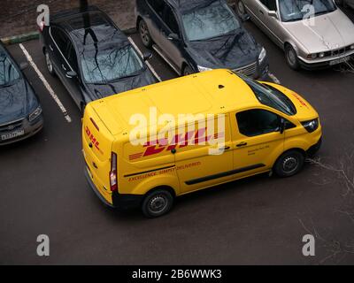 Mosca, Russia - 11 marzo 2020: Corriere DHL Deutsche Post in uniforme giallo-rossa vicino a un minivan con loghi aziendali. DHL International GmbH è la larg mondiale Foto Stock
