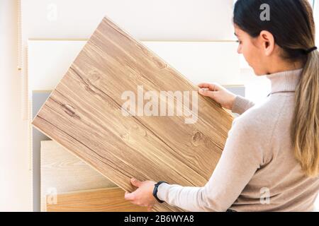 donna che sceglie pavimenti laminati in legno in negozio. riparazione casa Foto Stock