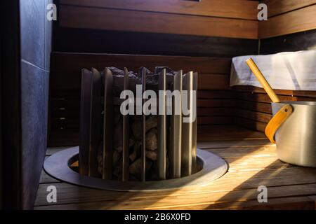 Bagno finlandese in legno con secchio e moderna stufa per sauna. Foto Stock