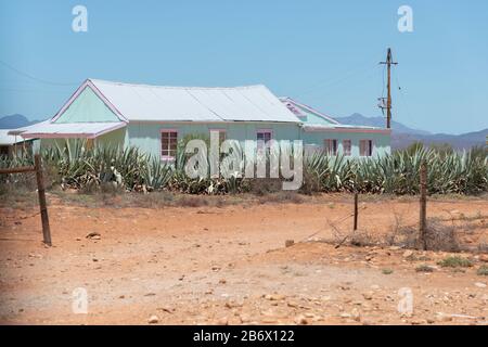 Tipica casa in metallo nel paesaggio arido alla periferia di Oudtshoorn, Capo Occidentale, Sud Africal Foto Stock