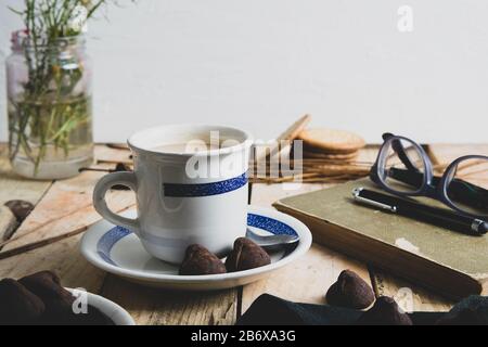 Una tazza di caffè accanto ad alcune note e una penna su un rustico tavolo di legno invecchiato. Spazio di copia vuoto per il testo dell'Editor. Foto Stock
