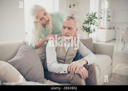 Qualcosa di sbagliato concetto. Foto di attenta e ottimista vecchia signora che fa massaggio per il suo sconvolto tenendo segreto sweetheart che è seduto sul divano in Foto Stock