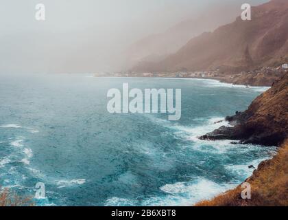 Paul Pombas, Santo Antao Capo Verde. La costa vulcanica di Bluff coperta dalla luce del sole penetra nella polvere. Silhouette di creste di montagna e onde oceaniche. Foto Stock