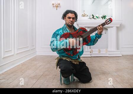 Uomo brutale Gypsy con una chitarra a cantare una canzone. Foto Stock