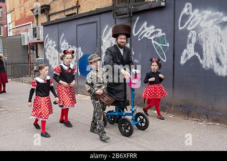 Un rabbino di Satmar attraversa Williamsburg con le sue figlie e il figlio in costumi Purim. Vicino A Lee Ave. A Williamsburg, Brooklyn, New York. Foto Stock