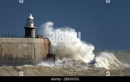 Le onde si infrangono contro le mura del porto durante le alte maree primaverili a Folkestone, nel Kent. Foto Stock