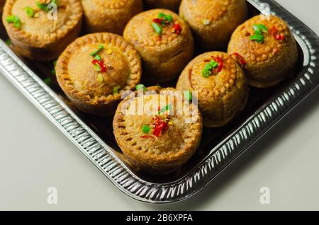 Tradizionali torte di maiale inglesi con salsa di mirtilli su vassoio d'argento, cibo inglese Foto Stock