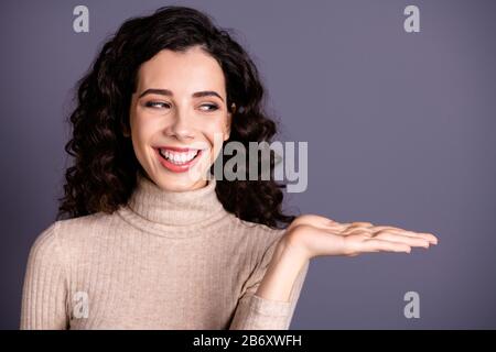 Ritratto primo piano di lei bella attraente simpatico allegro allegro felice positivo fiducioso donna ondulato-capelli che tiene invisibile annuncio pubblicitario oggetto Foto Stock