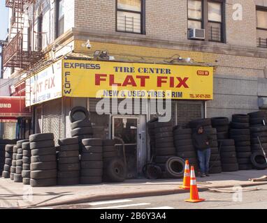 La parte anteriore di un negozio di riparazione pneumatici a Inwood, Manhattan con pneumatici impilati sul marciapiede Foto Stock