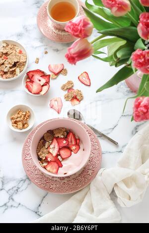 Tavolo luminoso per la colazione con yogurt, muesli e fragole secche Foto Stock