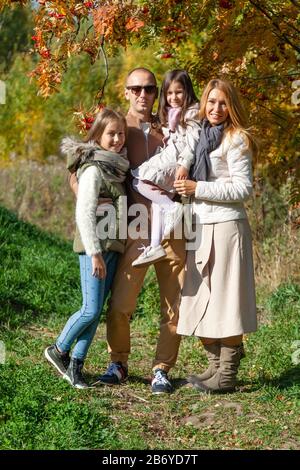 Famiglia felice, moglie, marito, figlie, camminare con i bambini, giocare nel parco autunnale, divertirsi nella foresta, rilassarsi all'aperto. Divertimento, infanzia, relax Foto Stock