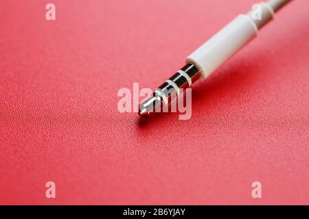 Connettore bianco cavo bianco ausiliario su sfondo rosso Foto Stock