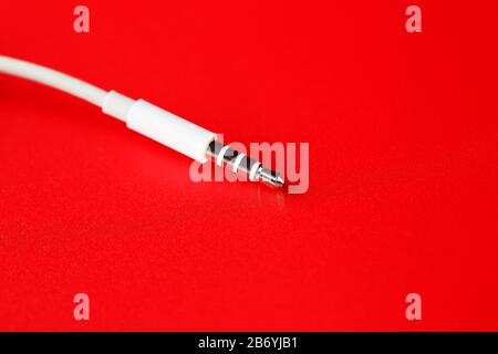 Connettore bianco cavo bianco ausiliario su sfondo rosso Foto Stock