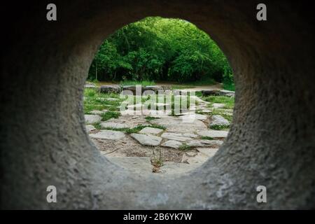 Vista interna di un dolmen di pietra attraverso un buco in una foresta di montagna nella valle del fiume Jean, Russia Foto Stock
