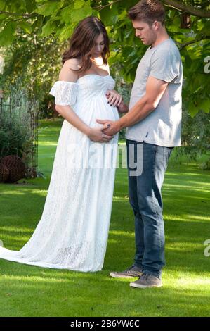 Bella donna incinta giovane e la sua partner che guarda preoccupato Foto Stock