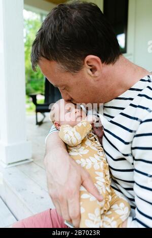 Un nuovo papà bacia la sua bambina neonato sulla fronte Foto Stock