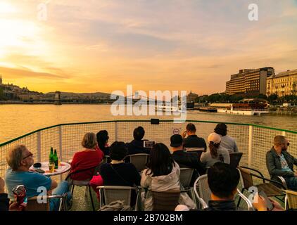 turisti che godono di vista del danubio da una barca da crociera al tramonto Foto Stock