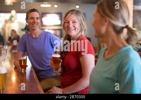 Tre amici femminili godono di una birra in una birreria nel campo governativo, O. Foto Stock