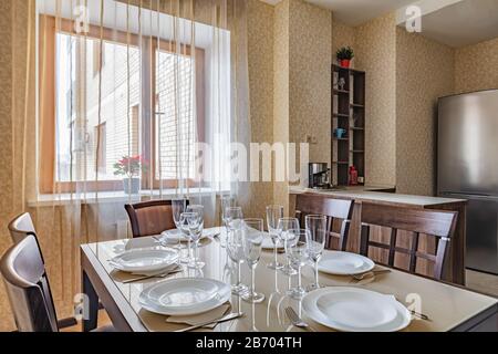 Preparato per cena tavolo da pranzo a casa. Bella piccola cucina beige interni alla luce del giorno Foto Stock