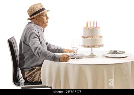 Uomo anziano che soffia candele su una torta isolata su sfondo bianco Foto Stock