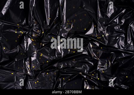 Tasca in plastica nera a perdere con fondo a tasca in polietilene con brillanti stelle dorate. Può essere utilizzato per le congratulazioni o la decorazione. Foto Stock